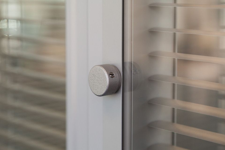 Круглая ручка на стеклянной двери с жалюзи