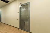 Дверь со стеклом и встроенными жалюзи, оснащенная доводчиком, в офисном коридоре