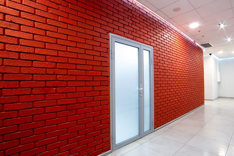 Двустворчатая алюминиевая дверь с матовым стеклом на фоне кирпичной стены