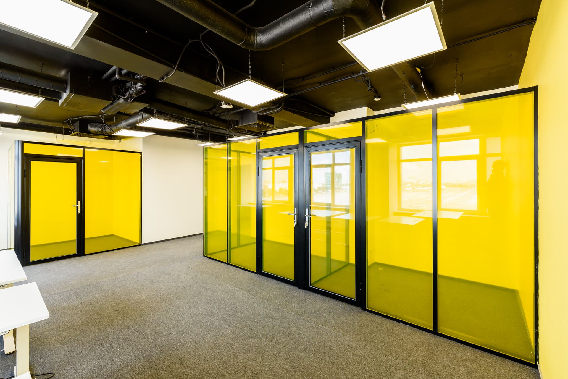 Линия желтых стеклянных перегородок с дверями в черном профиле
