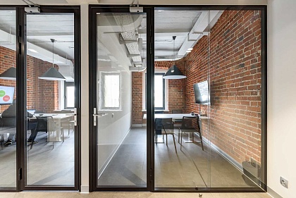 Стеклянные перегородки в черном профиле и распашные двери — пример офиса
