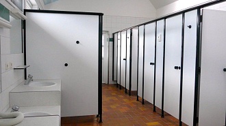 Туалетные перегородки для санузла: белые кабины и ряд дверей