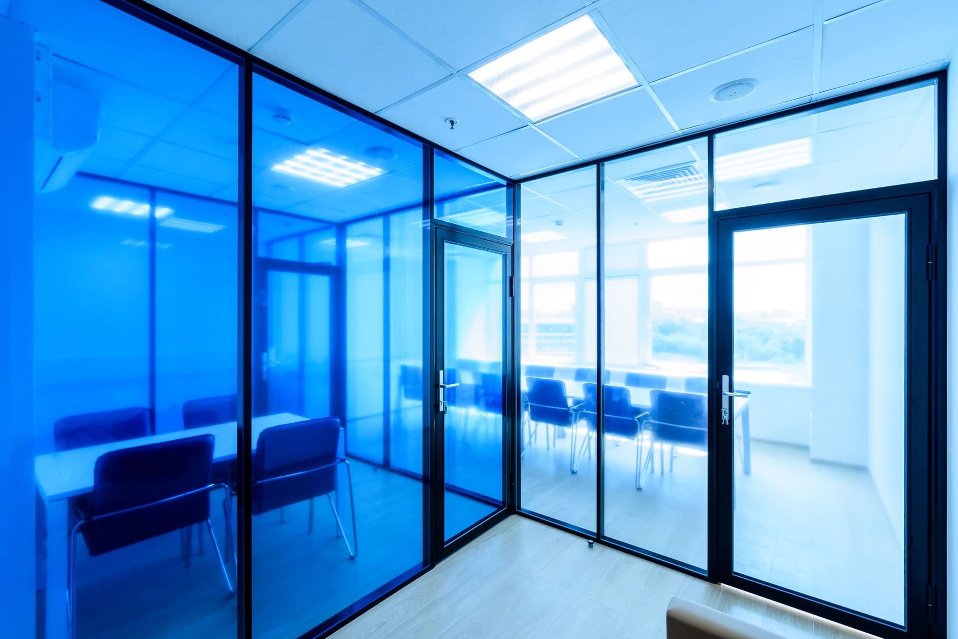 Угловое соединение синей и прозрачной стеклянной перегородки с дверью