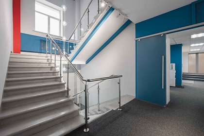 Входная зона у лестницы: дверь и стеклянные ограждения — пример интерьера